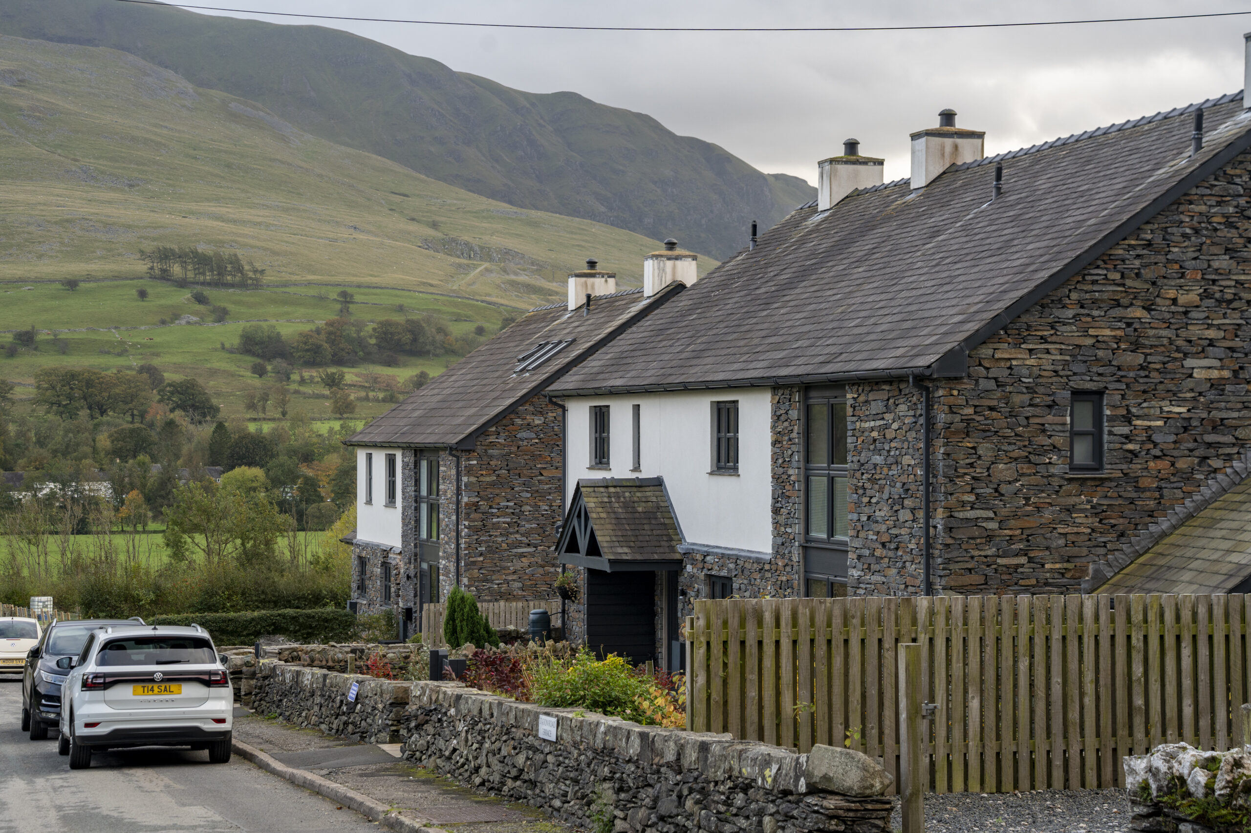 two semi-detached modern slate and lime wash rural houses on a quiet street with fells in the back drop