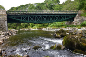 rich green metal bridge over wide river