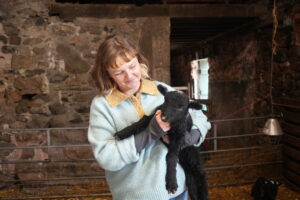 woman holding a lamb inside a farm building