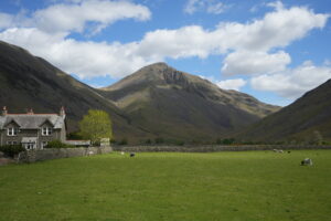 grey farmhouse building with fells in the background