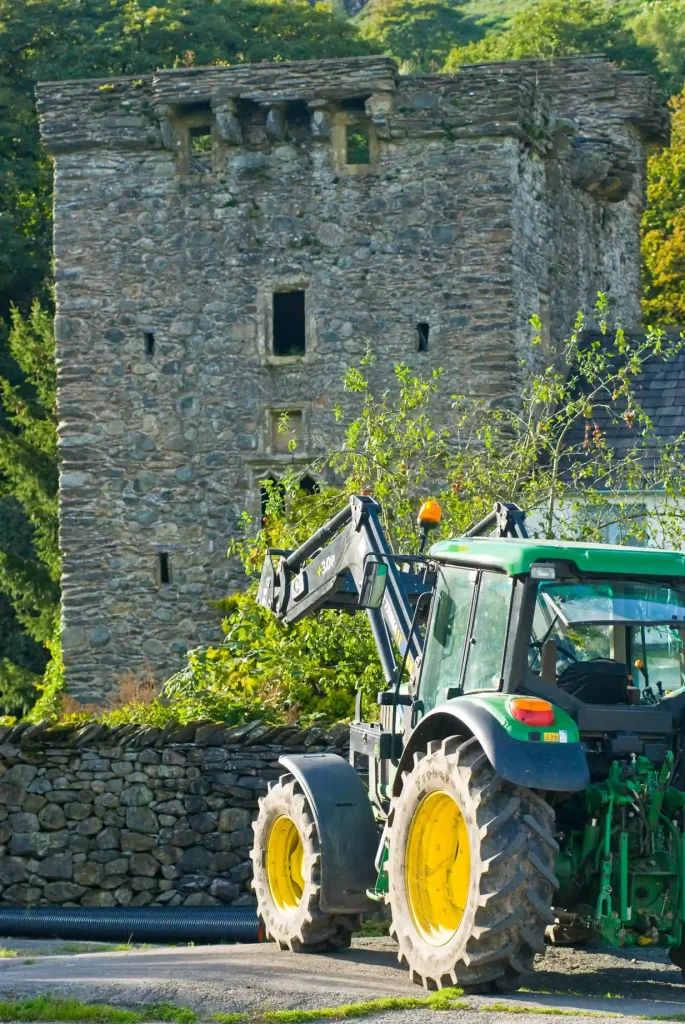 Green tracker on a village road with a stone barn behind